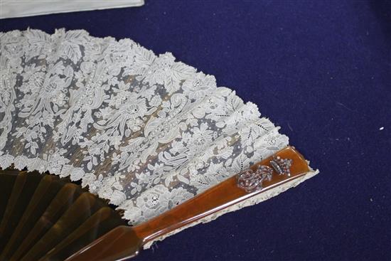 A Maison Patte-Hannot boxed lacework fan, with simulated amber sticks, inset with a rose diamond set crowned monogram, the lacework wit